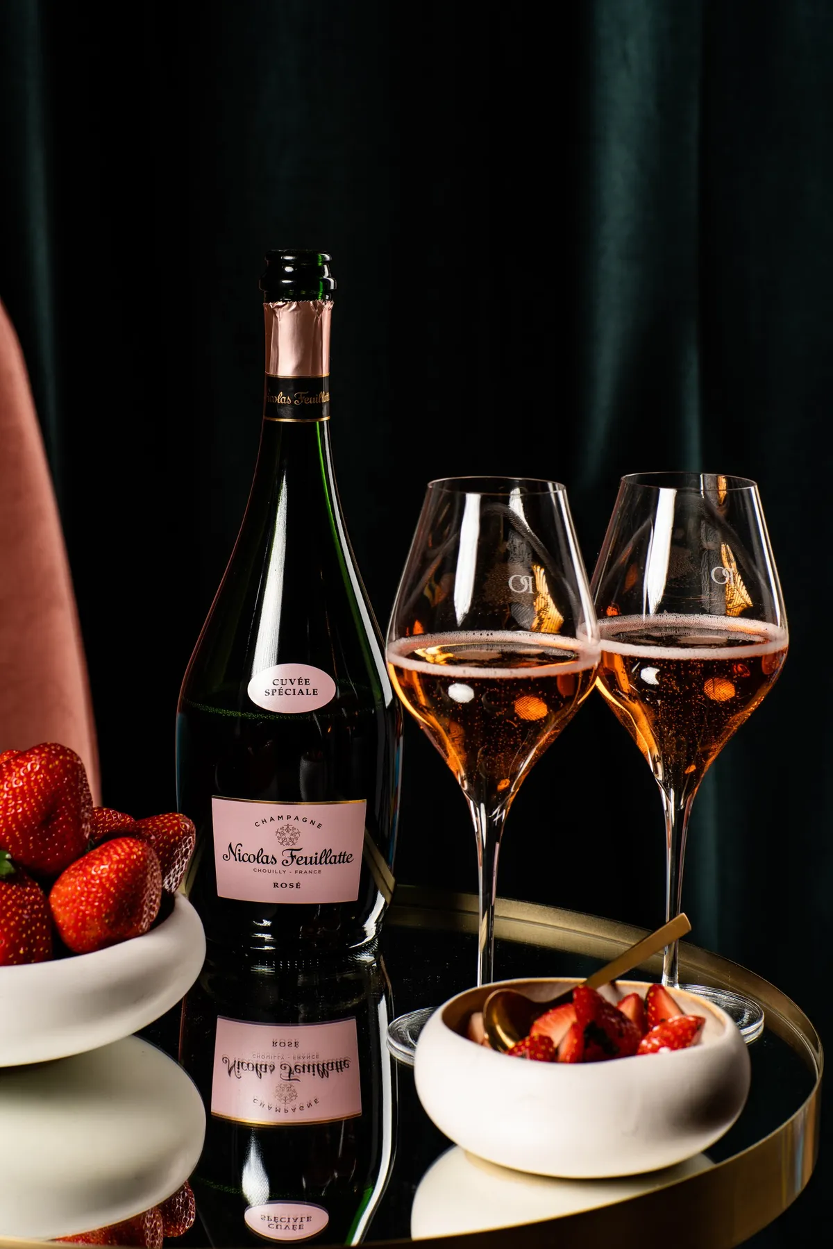Bottle of rosé champagne and two glasses beside bowls of strawberries, Nicolas Feuillatte