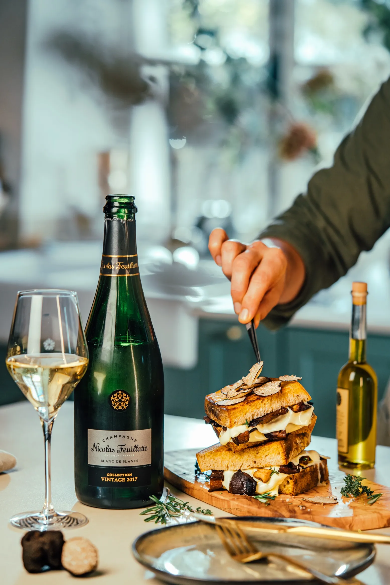 Bottle and glass of champagne next to a layered dessert being served, Nicolas Feuillatte food pairing