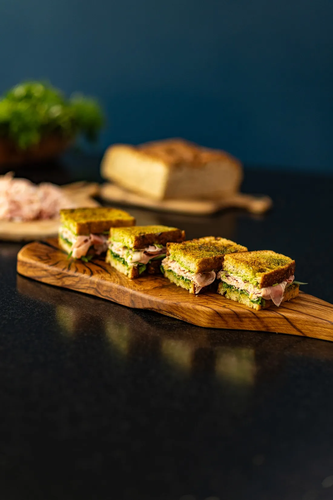 Ham and butter sandwich cut into bites on a wooden board, a loaf behind, food shot for Graille sur le rail