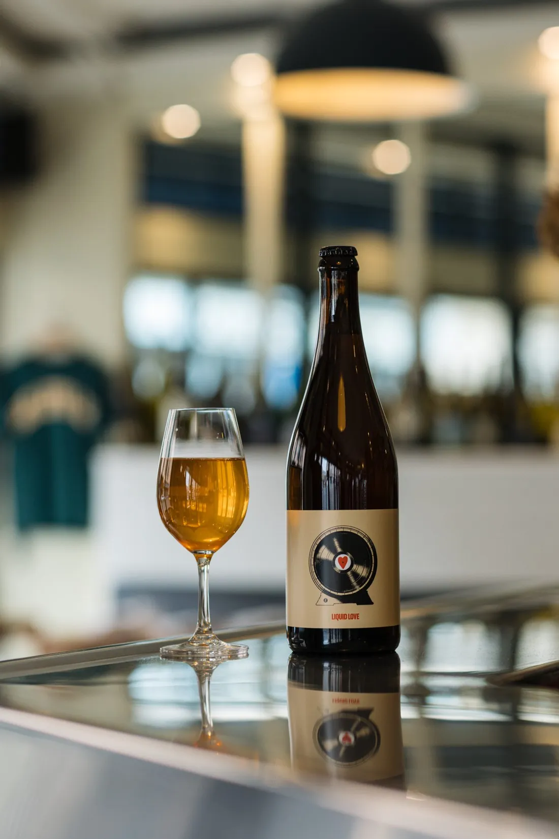 Bottle with a vinyl record label and a stemmed glass of beer on a bright bar counter, Hoppy Road brewery