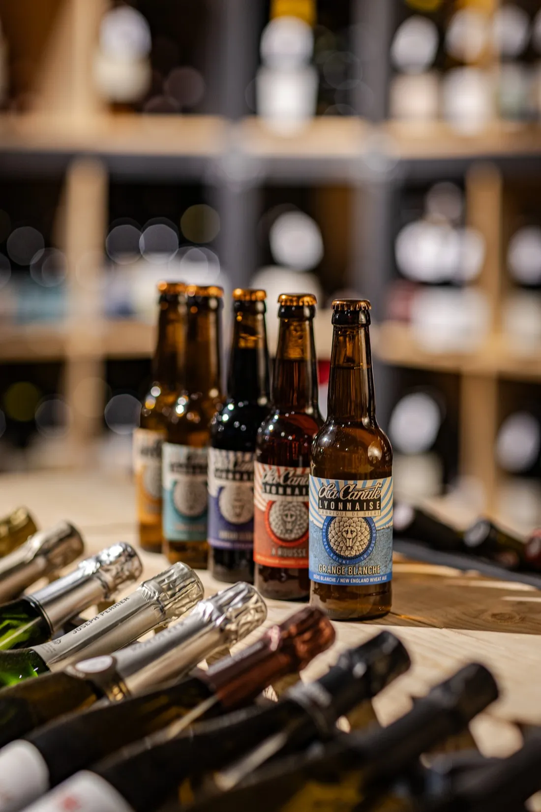 Bottles of La Canute Lyonnaise lined up on a wooden crate in a bottle shop, craft beer brewed in Lyon