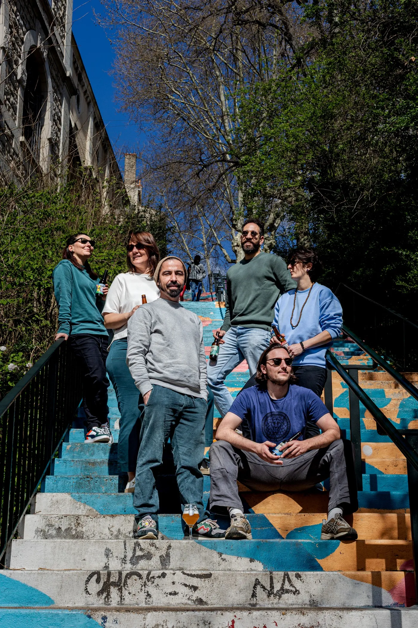 The brewery team posing on a painted staircase on the slopes of Lyon, La Canute Lyonnaise