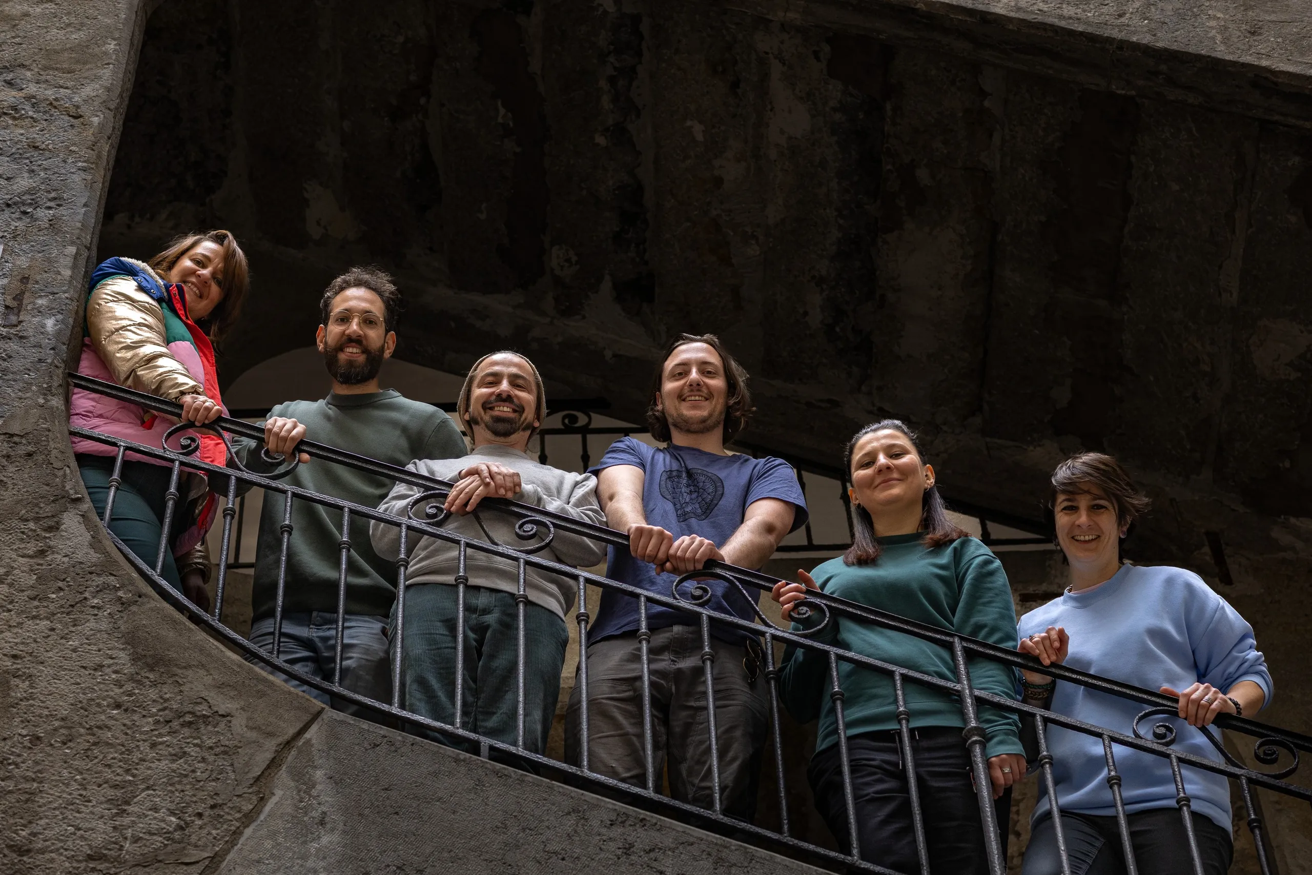 The team leaning on a wrought-iron railing in a stone stairwell, seen from below, La Canute Lyonnaise