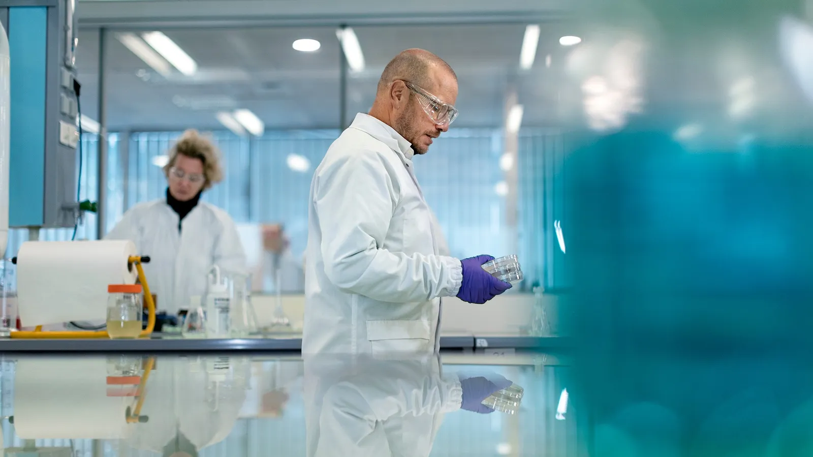 Two researchers in white coats at work in a bright laboratory, Le Monde & L'Oréal