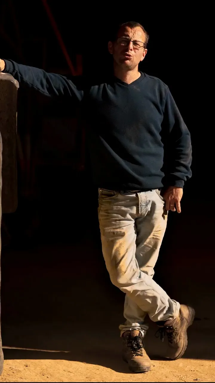 From generation to regeneration, the series: a farmer in a dark sweater leaning in a barn doorway, McCain