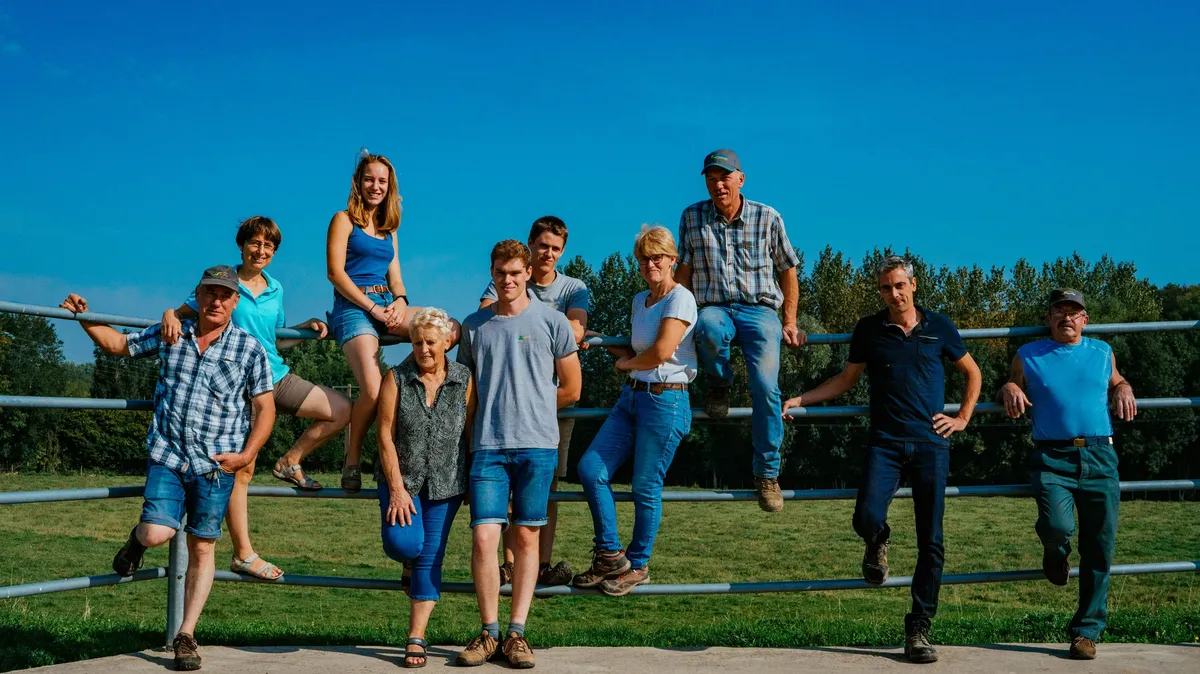 Farming family of all ages posing on a metal fence under a blue sky, McCain farming families
