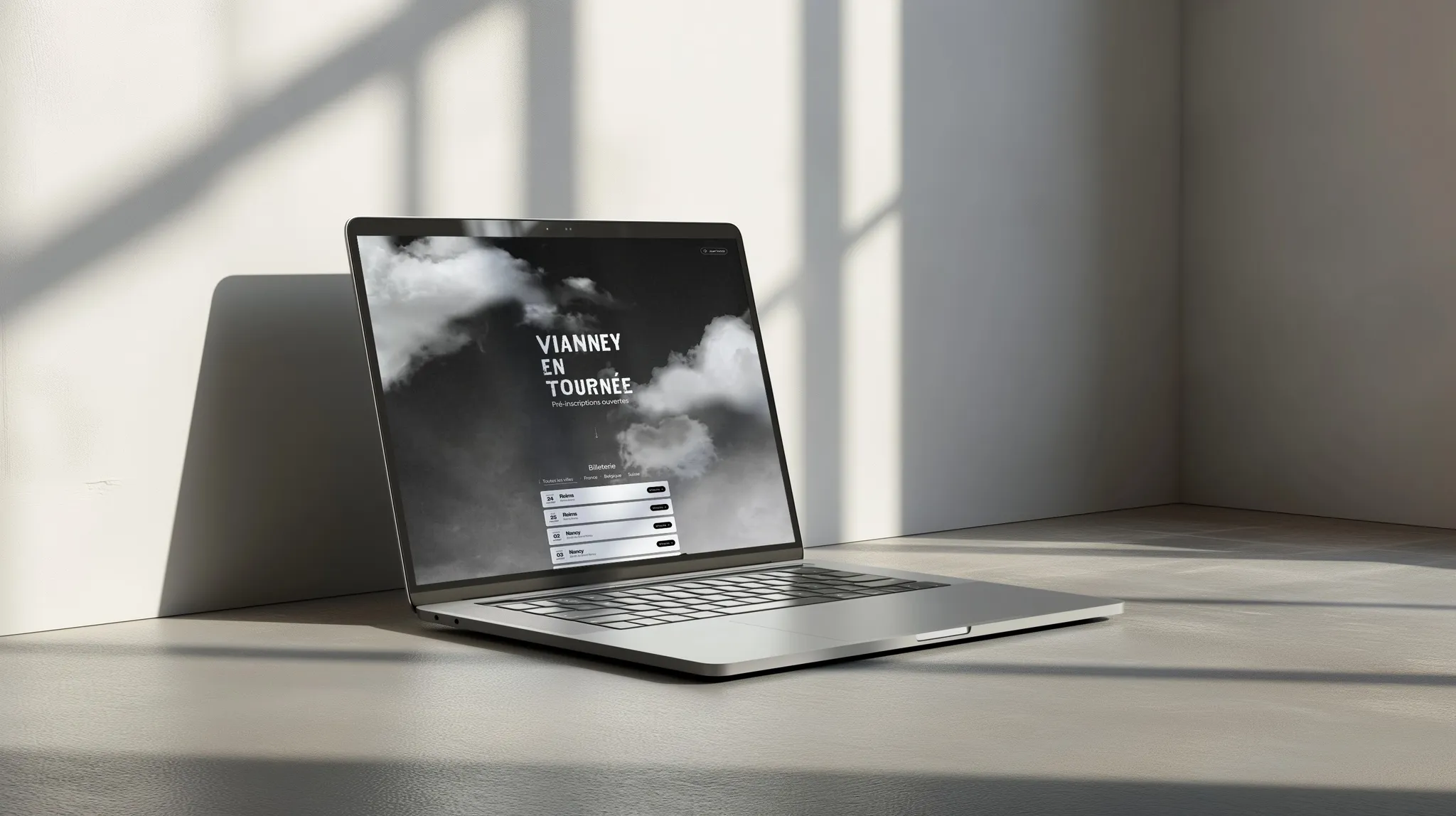 Laptop on a sunlit desk showing the Vianney en tournée website with its list of tour dates